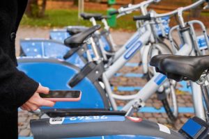 mloda kobieta placi smartfonem za wypozyczenie roweru